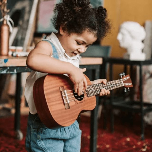Little girl playing a ukulele